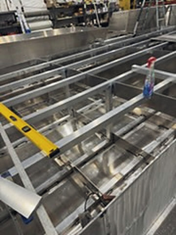 A hull framed out on the shop floor, a level across the ribs