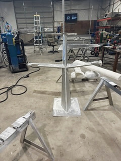 An aluminum mast welded to its base plate, the crossbar on