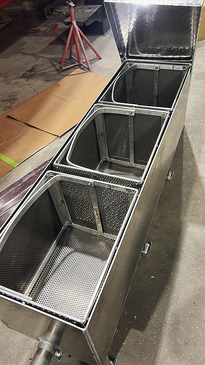 An aluminum box with three perforated baskets, lid up